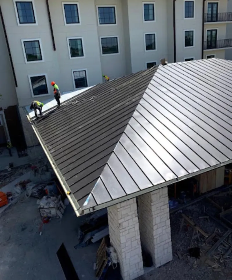 Crew installing standing seam metal roof panels on a commercial project in Villa Rica